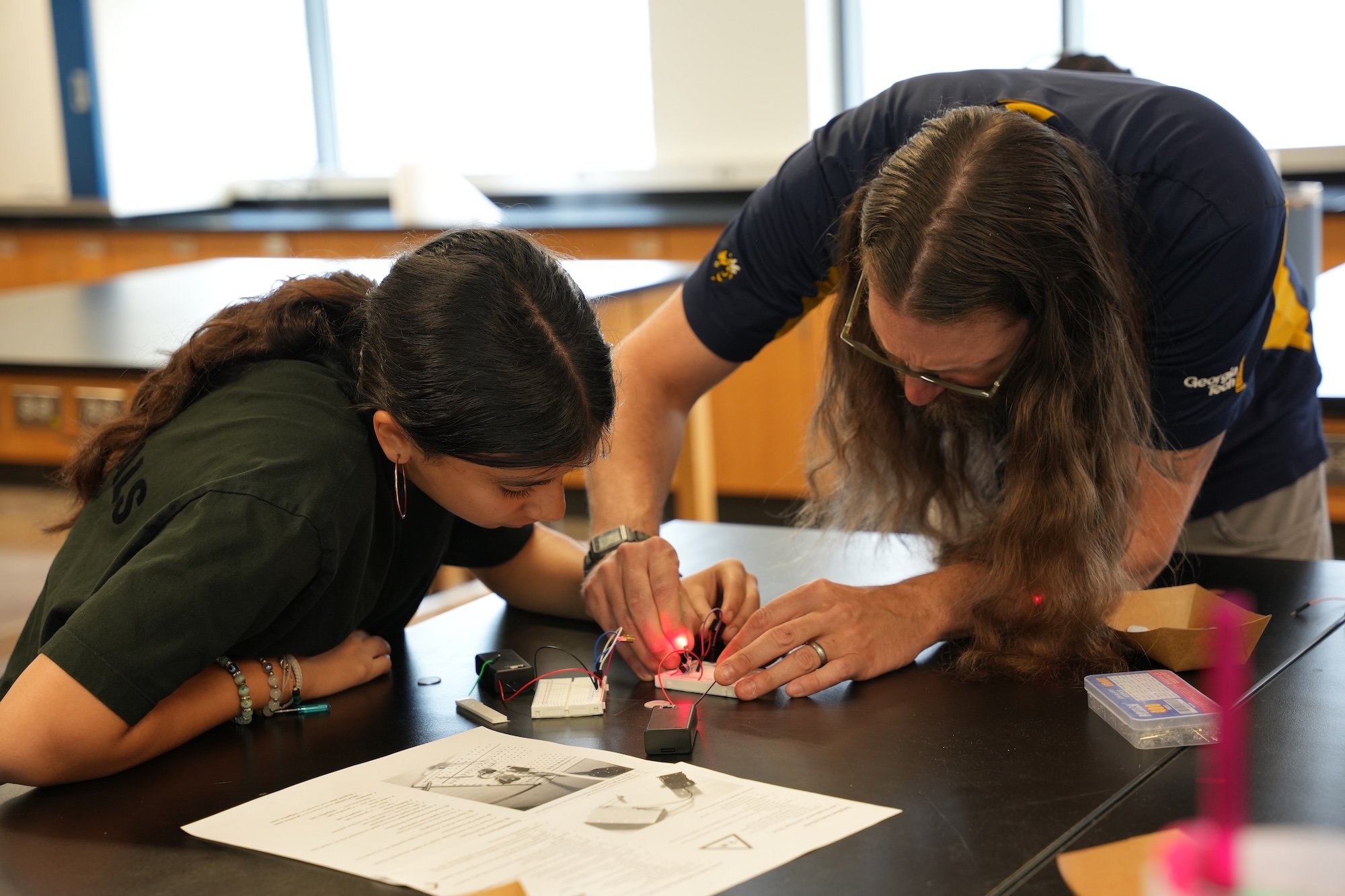 Instructor assists female student with science experiment.