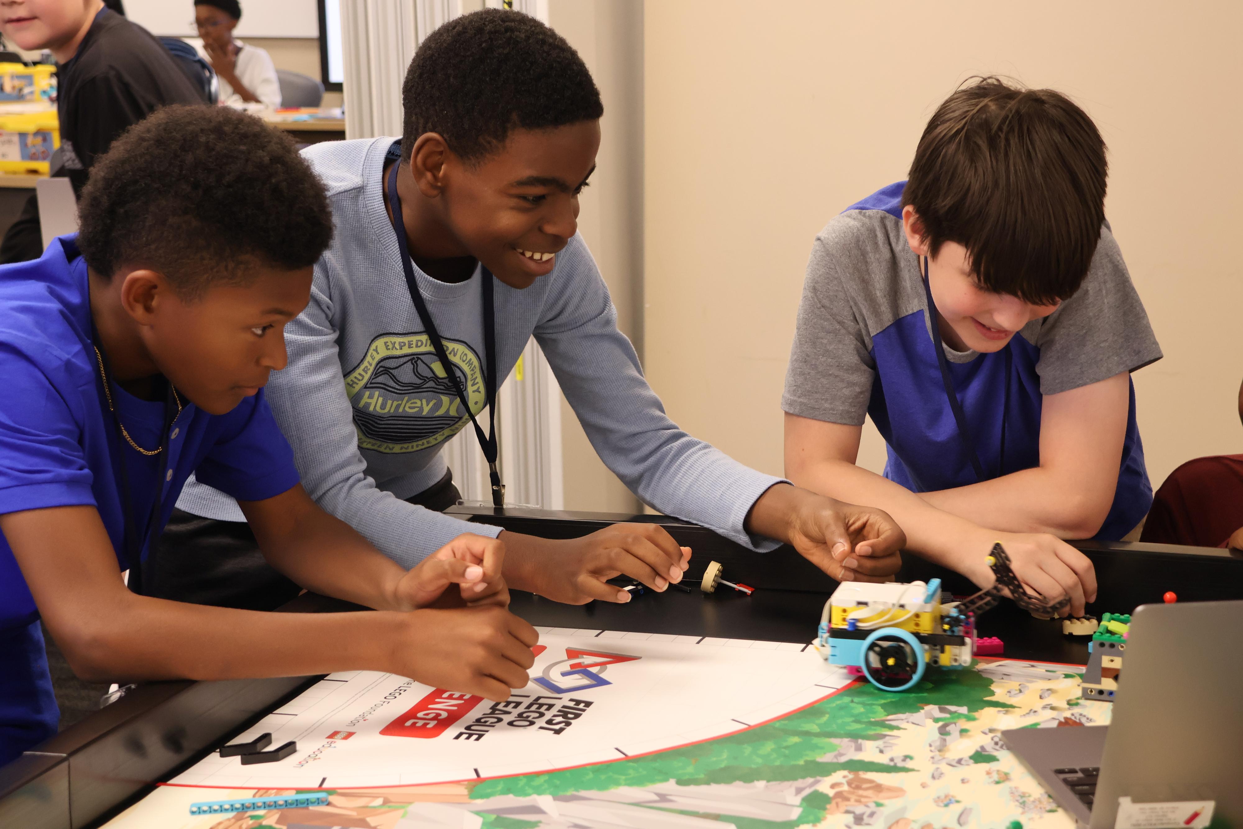 3 students building a LEGO robot.
